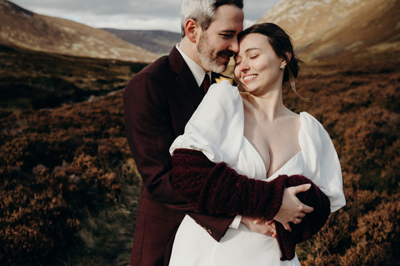 Bride and groom hug with hills in background